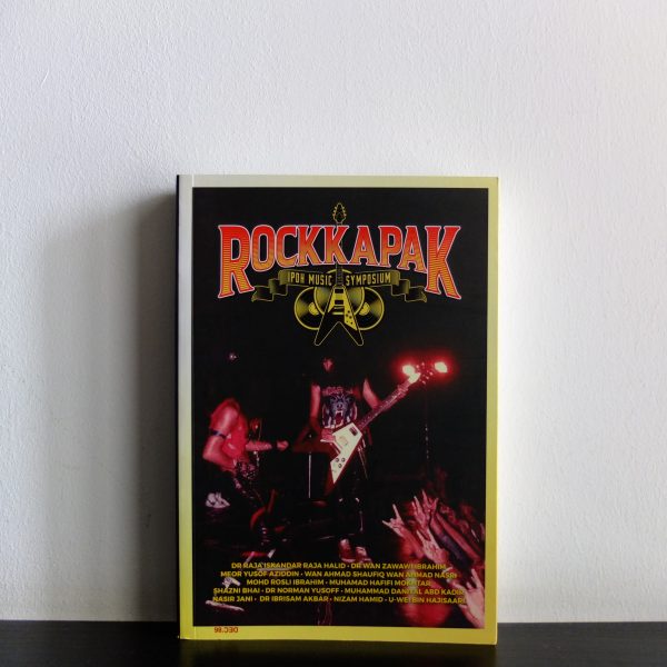 A book on a wooden furniture titled 'Muzik Rock Kapak' with a white wall background.